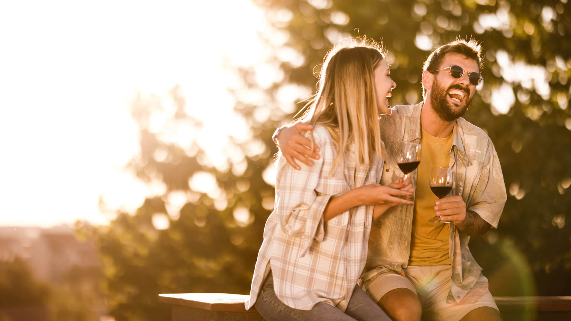 a couple drinking wine outside as the sun sets